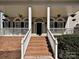 Inviting front porch with brick stairs, white railings, columns, and hanging plants creating a warm and welcoming entryway at 4407 Esherwood Ln, Charlotte, NC 28270