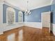 Bright living room with hardwood floors, two arched windows, a chandelier, wainscoting, and soft blue walls creating a cozy space at 4407 Esherwood Ln, Charlotte, NC 28270