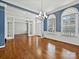 Open-concept room with hardwood floors, blue accent walls, two chandeliers, and large windows providing ample natural light at 4407 Esherwood Ln, Charlotte, NC 28270