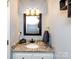 Bathroom with granite countertop vanity, three-light fixture, framed mirror, and sleek gray towel at 509 Baucom Deese Rd, Monroe, NC 28110