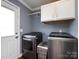 Well-lit laundry room boasts modern washer and dryer units with white cabinets and convenient storage space at 509 Baucom Deese Rd, Monroe, NC 28110