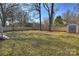 Fenced backyard with a grassy lawn, trees, and a fire pit, perfect for relaxation and recreation at 532 Scaleybark Rd, Charlotte, NC 28209