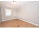 This bedroom has hardwood floors, light gray walls, white trim, and a window that provides natural light at 532 Scaleybark Rd, Charlotte, NC 28209