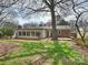 Exterior home view from the backyard with mature landscaping and a small deck at 833 Montford Dr, Charlotte, NC 28209