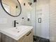 Well-lit bathroom features a modern vanity, subway tile shower with glass door, and sleek black hardware at 833 Montford Dr, Charlotte, NC 28209