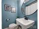 Cozy blue-painted bathroom features an elegant pedestal sink and modern fixtures, complemented by decorative art at 833 Montford Dr, Charlotte, NC 28209