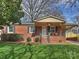 Charming brick home featuring a well-manicured lawn and inviting covered front porch with table set at 833 Montford Dr, Charlotte, NC 28209