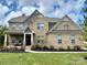 Charming two-story brick home with landscaped yard and welcoming front porch at 14018 Promenade Dr, Huntersville, NC 28078