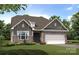 Charming exterior of home featuring stone and grey wood accents, a manicured lawn, and an attached two-car garage at 148 Prestwick Way # 21, Mooresville, NC 28115