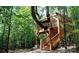 Unique treehouse structure nestled among the trees, featuring stairs and an elevated platform at 6289 Raven Rock Dr, Denver, NC 28037