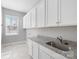 Laundry room with tiled floor, granite counters, stainless steel sink, and ample cabinet storage at 704 Kenway Loop, Mooresville, NC 28117