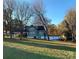 Spacious backyard showcasing a charming green home with a detached garage, surrounded by mature trees at 913 9Th Ne Ave, Hickory, NC 28601