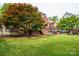 Expansive backyard featuring a large shade tree, patio with grill, and well-manicured lawn at 133 Castaway Trl, Mooresville, NC 28117