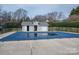 Covered community pool with a light gray pool house, surrounded by an iron fence and mature trees at 133 Castaway Trl, Mooresville, NC 28117