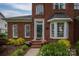 Close-up of the front entrance with a glass front door, brick facade, and colorful potted plants at 133 Castaway Trl, Mooresville, NC 28117