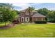 Charming two-story red brick home with well-manicured lawn, mature trees and landscaping, under a sunny sky at 133 Castaway Trl, Mooresville, NC 28117