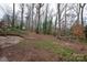 Wooded backyard with a stone retaining wall and patio at 218 Kingsway Cir, Charlotte, NC 28214