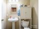 Clean bathroom with pedestal sink, toilet, and storage cabinet at 535 Tyson St, Charlotte, NC 28209