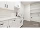 Bright laundry room with white cabinets, a utility sink, and built-in shelving at 10517 S Hampton Dr, Charlotte, NC 28227