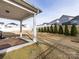 Covered patio with string lights, overlooking a backyard with trees and a neighboring house at 11021 Ogden Ln, Charlotte, NC 28278