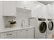 Modern laundry room with white cabinets and matching washer/dryer at 130 Cherokee Rd # 403, Charlotte, NC 28207