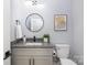 Modern bathroom with granite countertop, gray cabinets and a round mirror at 1938 Grace Ln, Charlotte, NC 28262