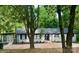 Well-maintained one-story home with black trim has a driveway and mature trees offering natural shade at 217 Ruby Ln, Gastonia, NC 28054