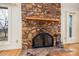 Close up of living room fireplace with unique stone work, tile hearth, wood floors, and nearby window at 33287 Mann Rd, Albemarle, NC 28001