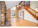 Open living room features a large window, wood floors, a stone fireplace, and a staircase leading to a loft area at 33287 Mann Rd, Albemarle, NC 28001