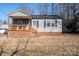 Gray siding house with brick base, wooden porch, and mature trees in the yard at 604 Kimball St, Kannapolis, NC 28081