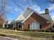 Brick ranch home with a gray roof, arched windows, and landscaping at 8355 Olde Troon Dr, Charlotte, NC 28277