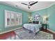 Bedroom with a teal accent wall, hardwood floors, and a large window at 10718 Lederer Ave, Charlotte, NC 28277