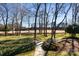 Inviting front yard featuring a stone walkway, lush landscaping, and mature trees overlooking the golf course at 12201 Pine Valley Club Dr, Charlotte, NC 28277