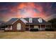 Brick ranch home with stone accents, a large front porch, and a beautiful sunset at 1270 Mirror Lake Rd, Lincolnton, NC 28092