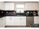 Modern kitchen with white cabinets, a large sink, and dark countertops at 131 Crownpiece St, Troutman, NC 28166