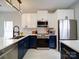 Modern kitchen with stainless steel appliances, white upper cabinets, and contrasting blue base cabinets at 17004 Commons Creek Dr, Charlotte, NC 28277