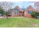 Charming brick home boasts a manicured lawn and inviting red door, complete with mature trees at 1915 Cavendale Dr, Rock Hill, SC 29732