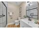 Modern bathroom features a glass shower, white vanity, black hardware, decorative art and wood-look vinyl plank flooring at 407 Thomas St, Marshville, NC 28103