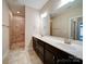 Bathroom with a double sink vanity, framed mirrors, walk-in shower, and tiled floor offering a modern and functional space at 9029 Treetop Nw Way, Concord, NC 28027