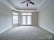 Expansive bedroom with tray ceiling, ceiling fan, and access to the outside through double doors, bathed in natural light at 9029 Treetop Nw Way, Concord, NC 28027