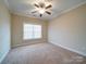 A well-lit bedroom showcasing plush carpet, a ceiling fan, and a large window, creating a comfortable and relaxing environment at 9029 Treetop Nw Way, Concord, NC 28027