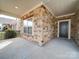 Inviting front porch features brick accents, a black front door, and a cozy, covered seating area at 9029 Treetop Nw Way, Concord, NC 28027