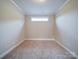 A cozy room with neutral carpet and walls, featuring a small window for natural light at 9029 Treetop Nw Way, Concord, NC 28027