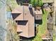 An aerial shot of the house showing the roof, landscaping, trees, backyard patio and bordering fence at 10433 Pullengreen Dr, Charlotte, NC 28277