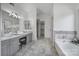 Elegant bathroom featuring double sinks, tiled floors, soaking tub, and glass-enclosed shower at 10433 Pullengreen Dr, Charlotte, NC 28277