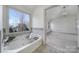 Bright bathroom with a large window view, tile backsplash, and a soaking tub with a wooden tray at 10433 Pullengreen Dr, Charlotte, NC 28277