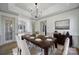 Traditional dining room features wainscoting, modern chandelier, and a large table set for six at 10433 Pullengreen Dr, Charlotte, NC 28277