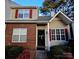 Inviting townhome featuring red shutters, brick facade, and manicured landscaping at 10904 Pimlico Dr, Charlotte, NC 28273