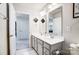 Bright bathroom with double sinks, and gray vanity cabinets with view to hall at 1328 Lena St, Monroe, NC 28112