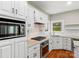 Bright kitchen showcasing white cabinets, stone countertops, stainless steel appliances, a window and hardwood flooring at 5972 Rathlin Nw Ct, Concord, NC 28027